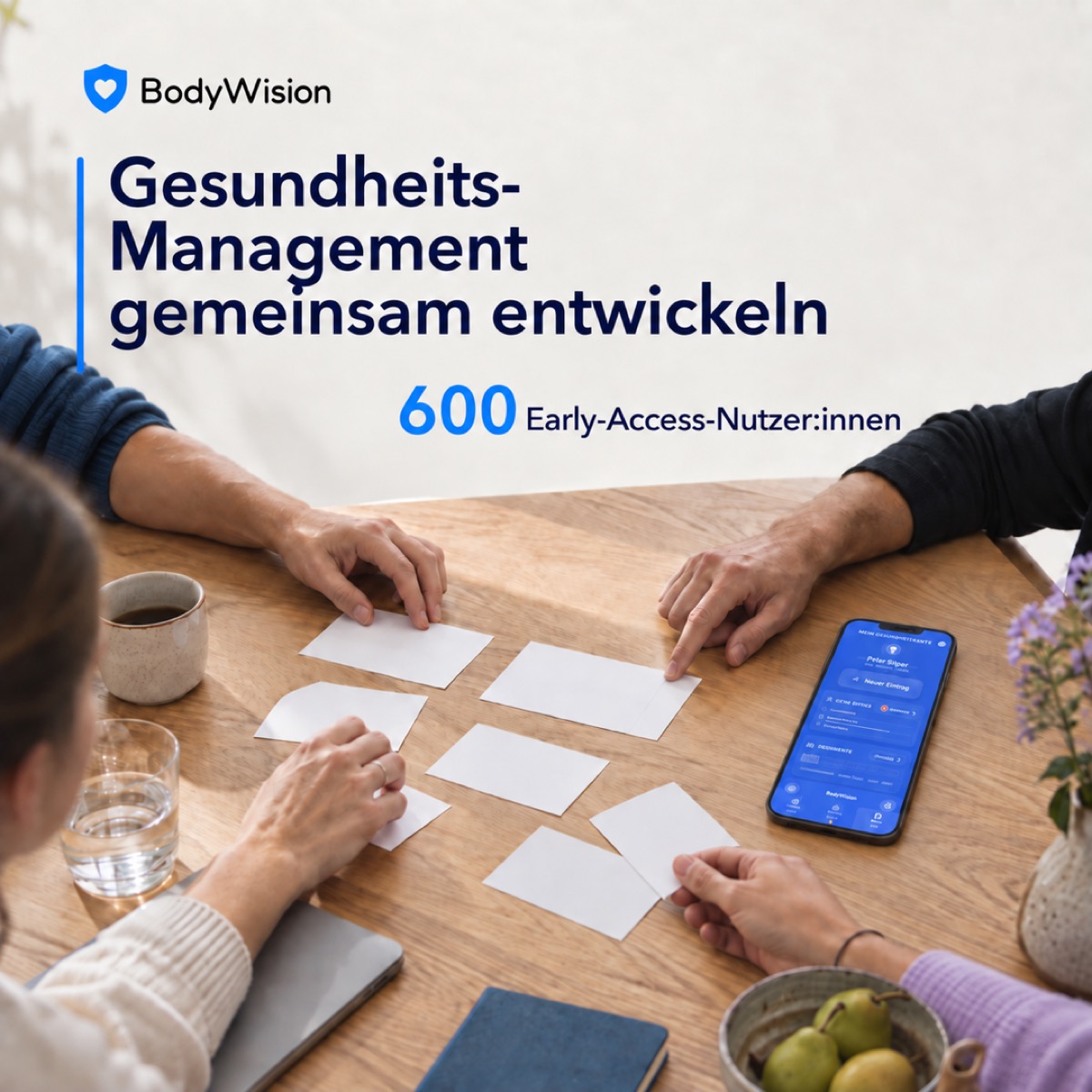 Gesundheits-Management gemeinsam entwickeln: 600 Early-Access-Nutzer:innen, Co-Design am Tisch und die BodyWision-Gesundheitsakte auf einem Smartphone.